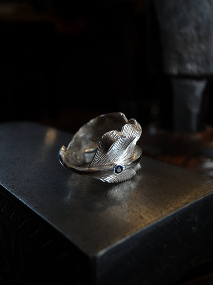 A sterling silver feather ring made using traditional repousse and chasing techniques. It is set with a blue sapphire.
