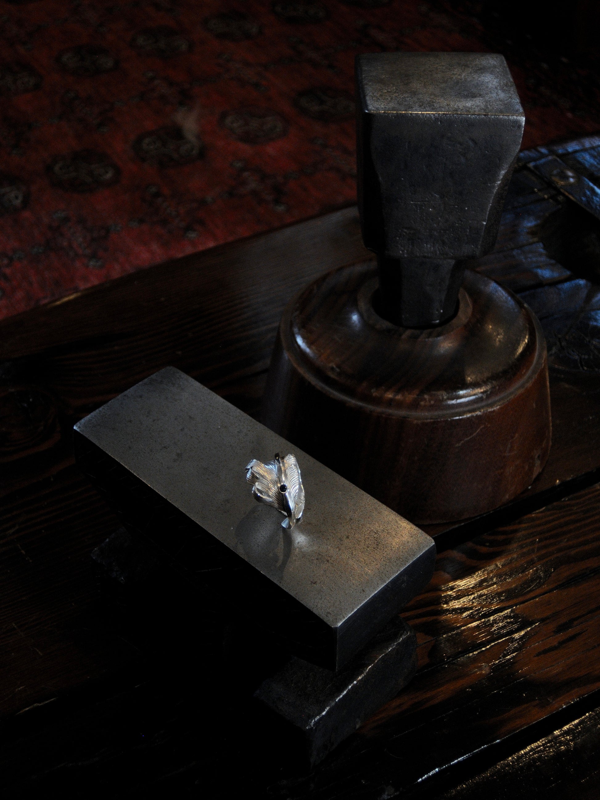 A sterling silver feather ring made using traditional repousse and chasing techniques. It is set with a blue sapphire.
