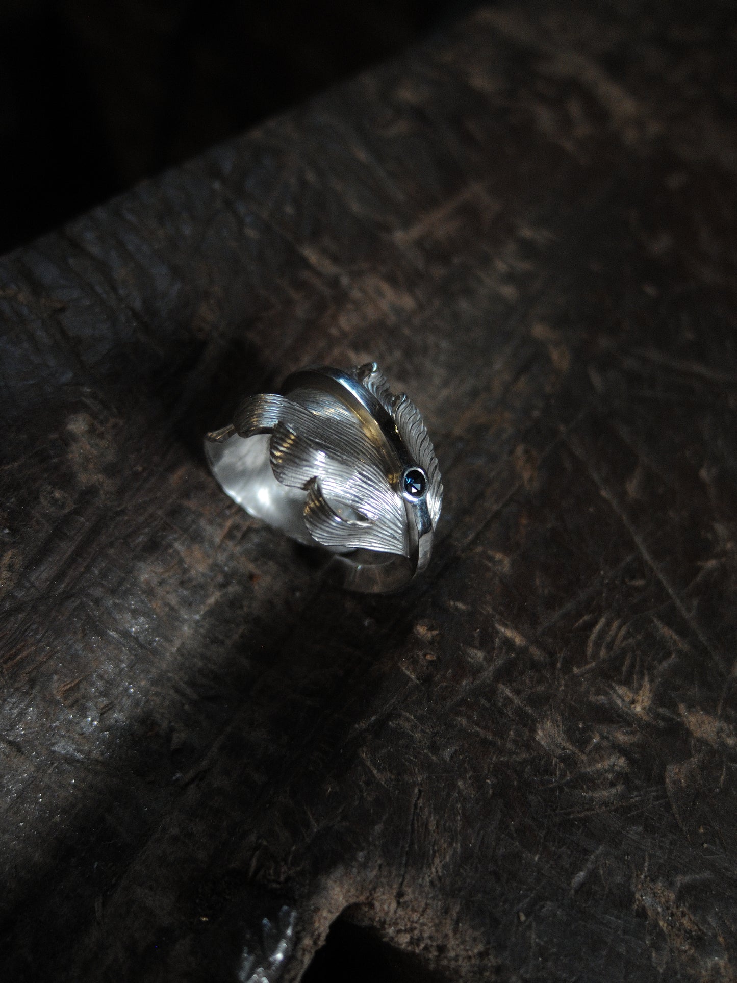 A sterling silver feather ring made using traditional repousse and chasing techniques. It is set with a blue sapphire.