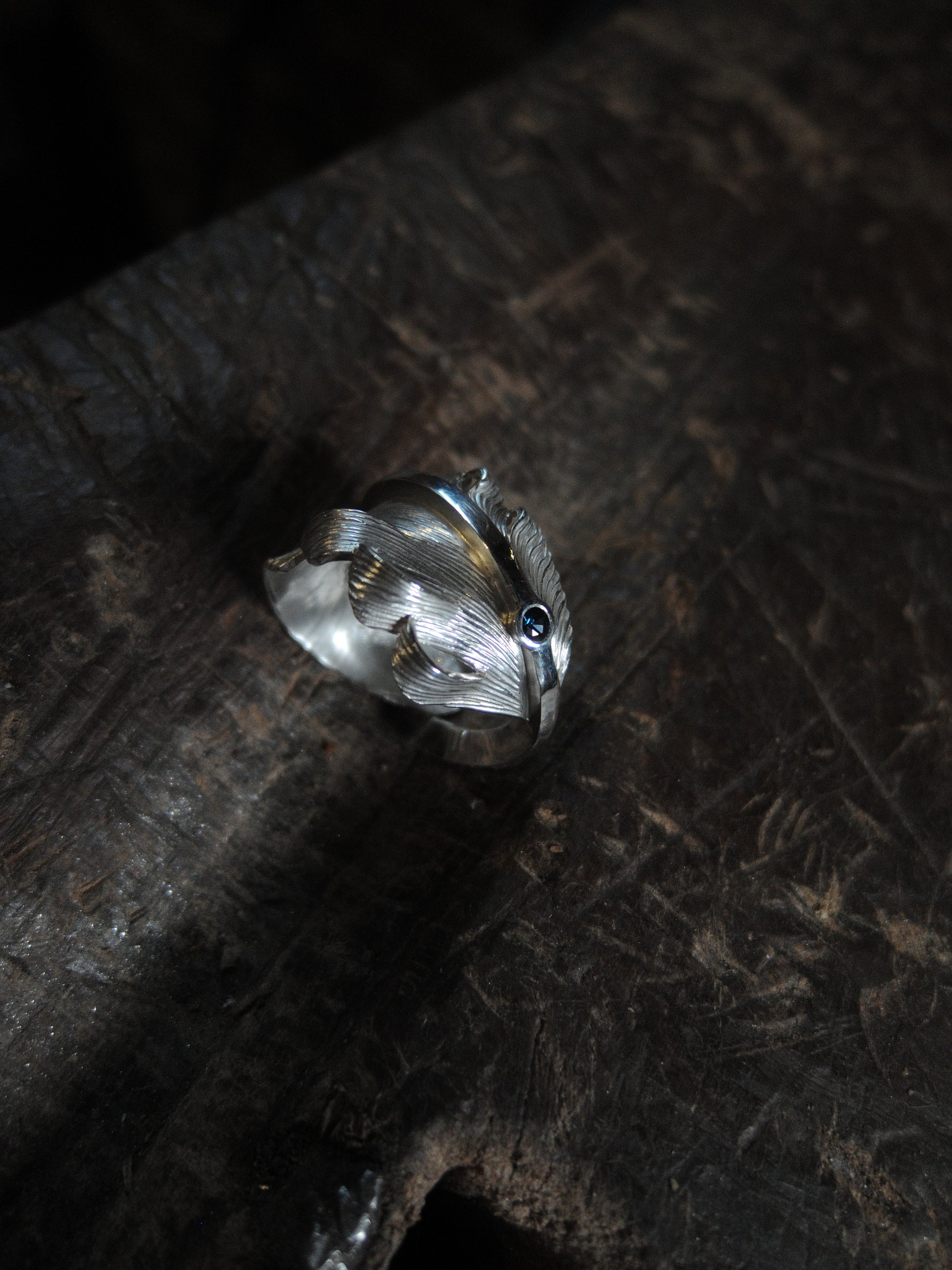 A sterling silver feather ring made using traditional repousse and chasing techniques. It is set with a blue sapphire.